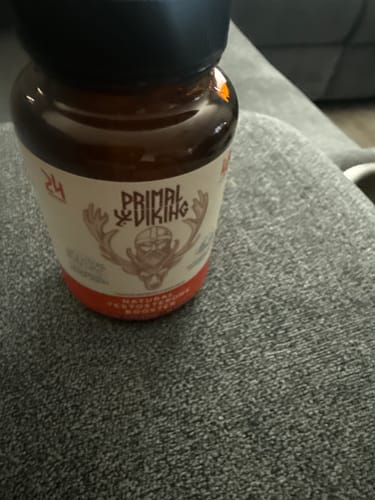 Customer's Primal Testosterone Booster bottle, close-up, sitting on a grey couch.