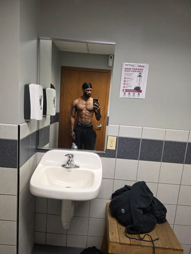 Customer's muscular physique in a gym mirror, reflecting results from the Ancestral Testosterone Booster.
