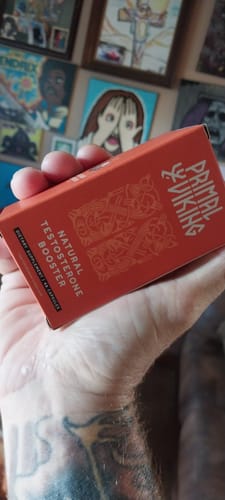 Customer's hand holding a red Primal Testosterone Booster product box with bold branding.