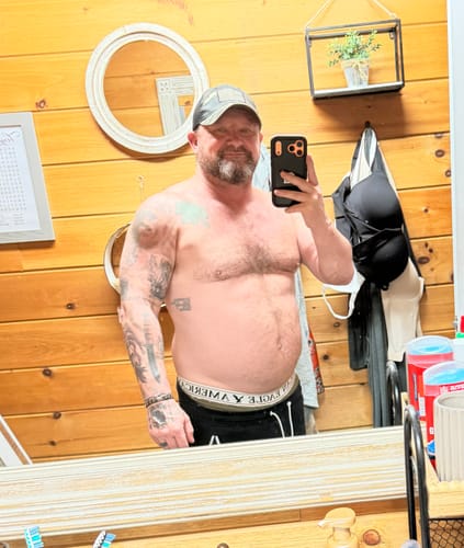 Customer's mirror selfie showing physical progress, a 54-year-old reviewer using Primal Testosterone Booster.