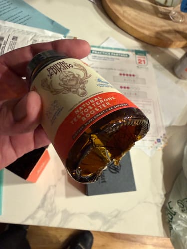 Customer's Primal Testosterone Booster bottle held in hand, showing a damaged bottom.