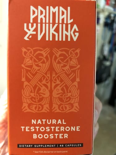 A reviewer holding the orange box of Primal Viking Natural Testosterone Booster.